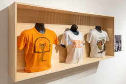 Queer Miami exhibition | Artifact case filled with historic t-shirts